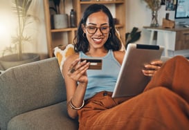 Adobe stock photo of woman lounding at home in the summer paying for online purchase with credit card