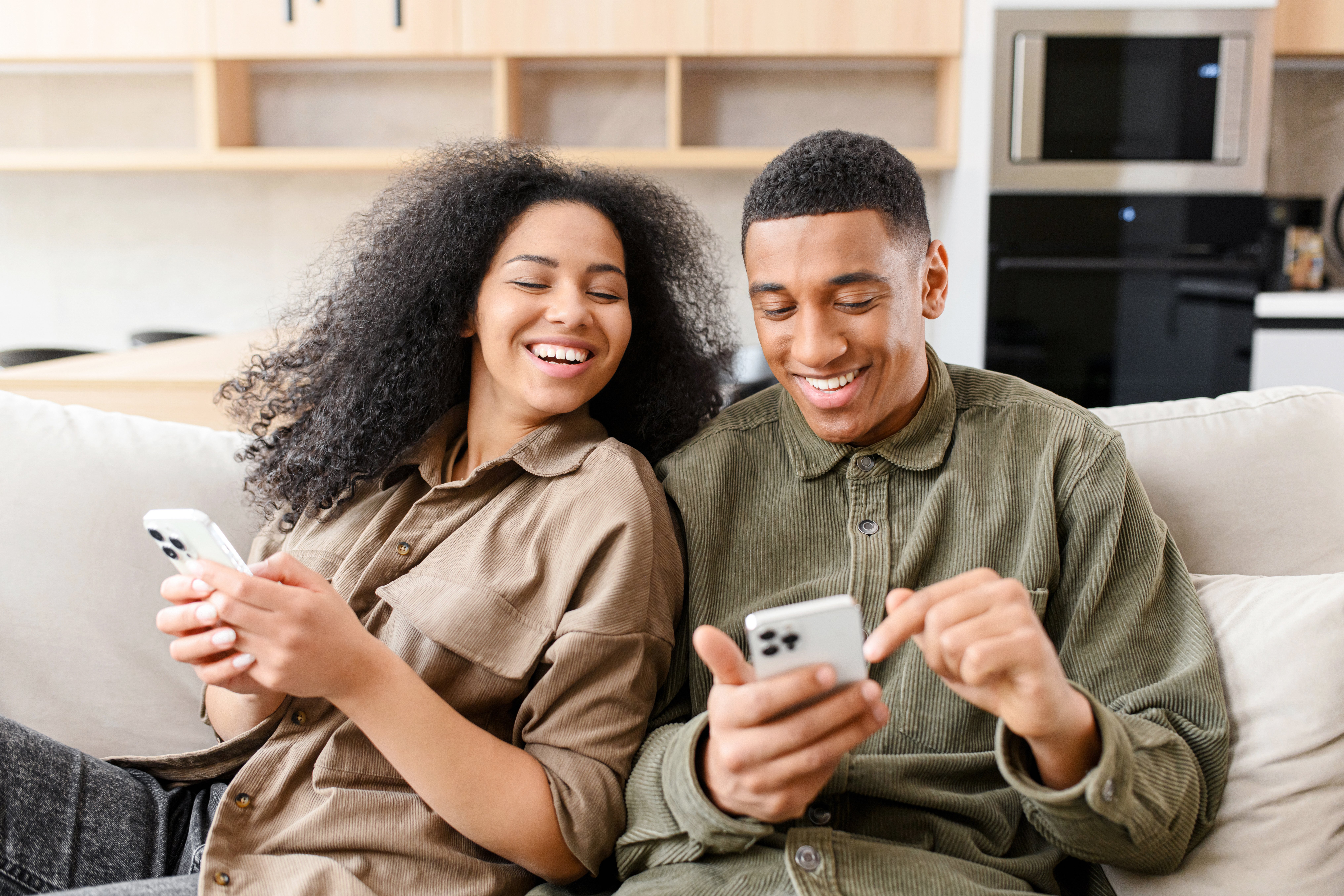 Woman sitting at the couch and looking at the smartphone of her boyfriend