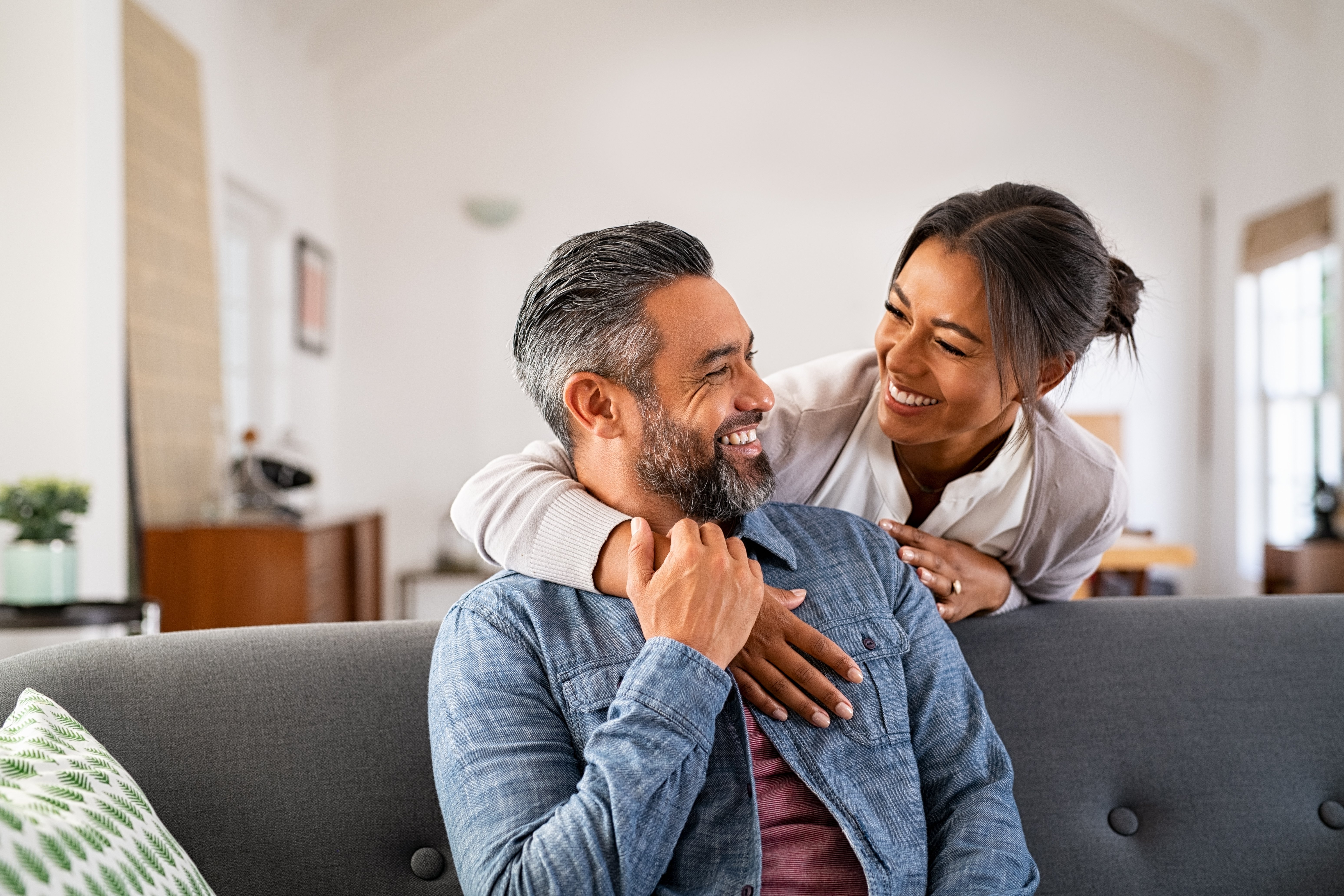 Mature multiethnic couple laughing and embracing at home adobe stock image