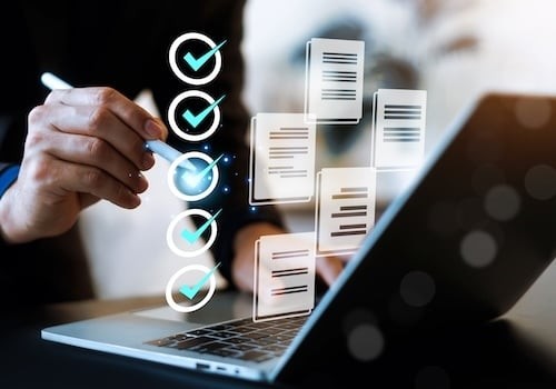 Professional businessman using a laptop with digital checklist and document icons. This conceptual image represents task management, quality assurance, workflow automation, paperless office.