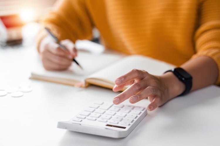 Close up asian women is keeping a record of her income and expenses, she plans her finances by using his monthly savings to buy funds to make it grow faster.