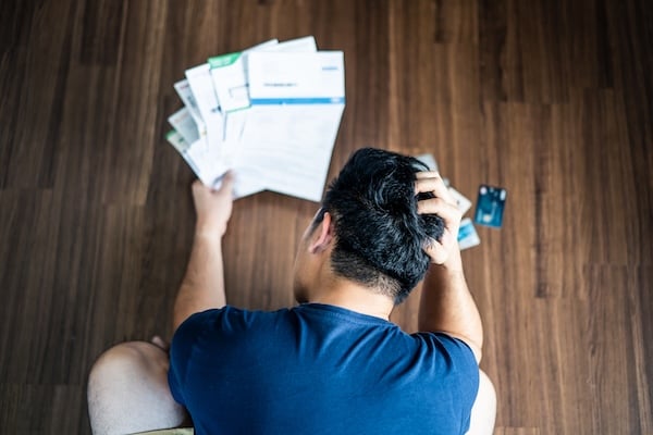 Top view of stressed young Asian man hands holding the head trying to find money to pay credit card debt and all loan bills