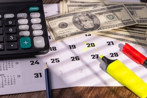 Calendar page with highlighted tax payment date near corporate calculator and red markers on workspace desktop background.