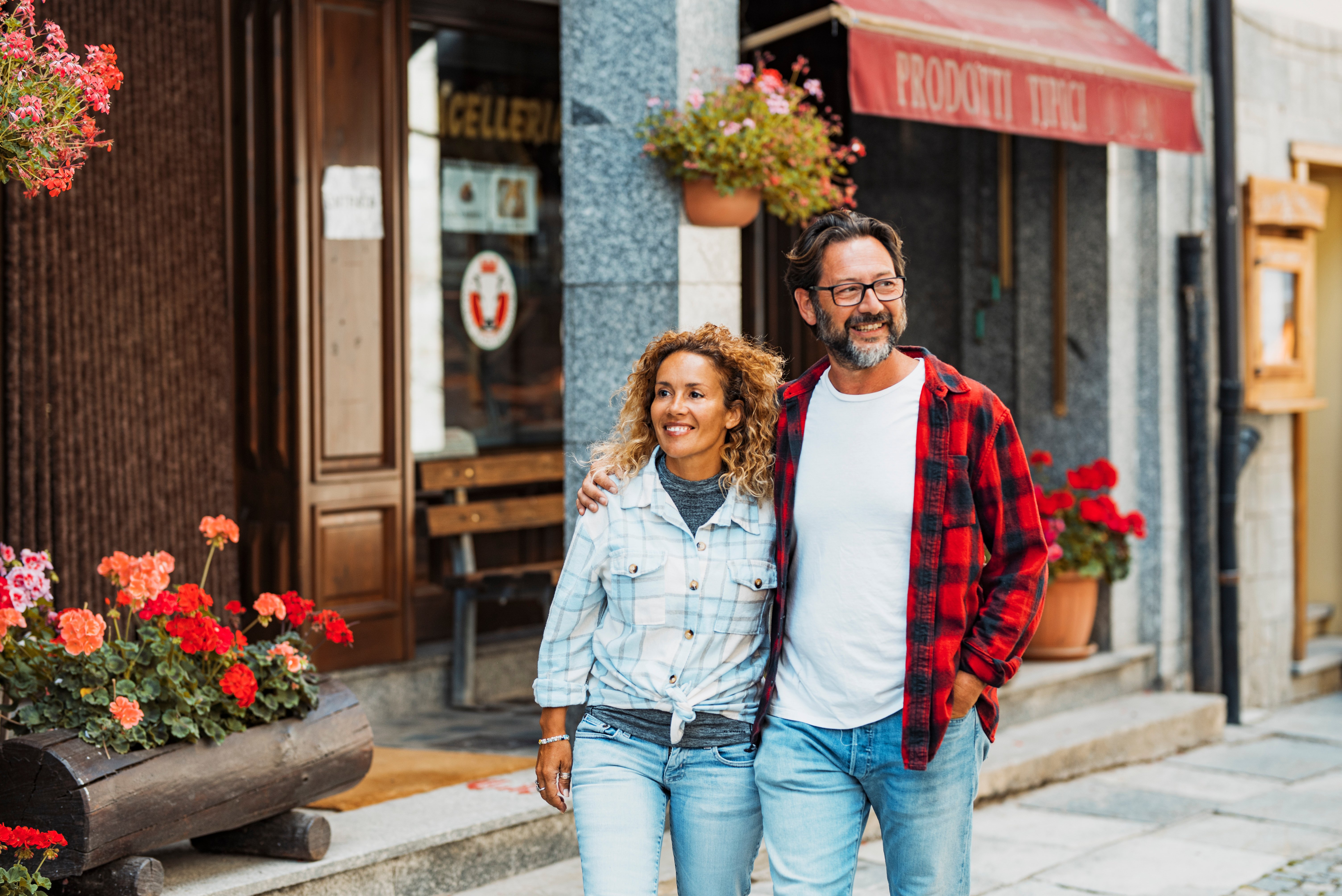 Happy adult young couple of tourist walking together in the street shops town and smiling looking around. Mountain and spring summer holiday vacation people.