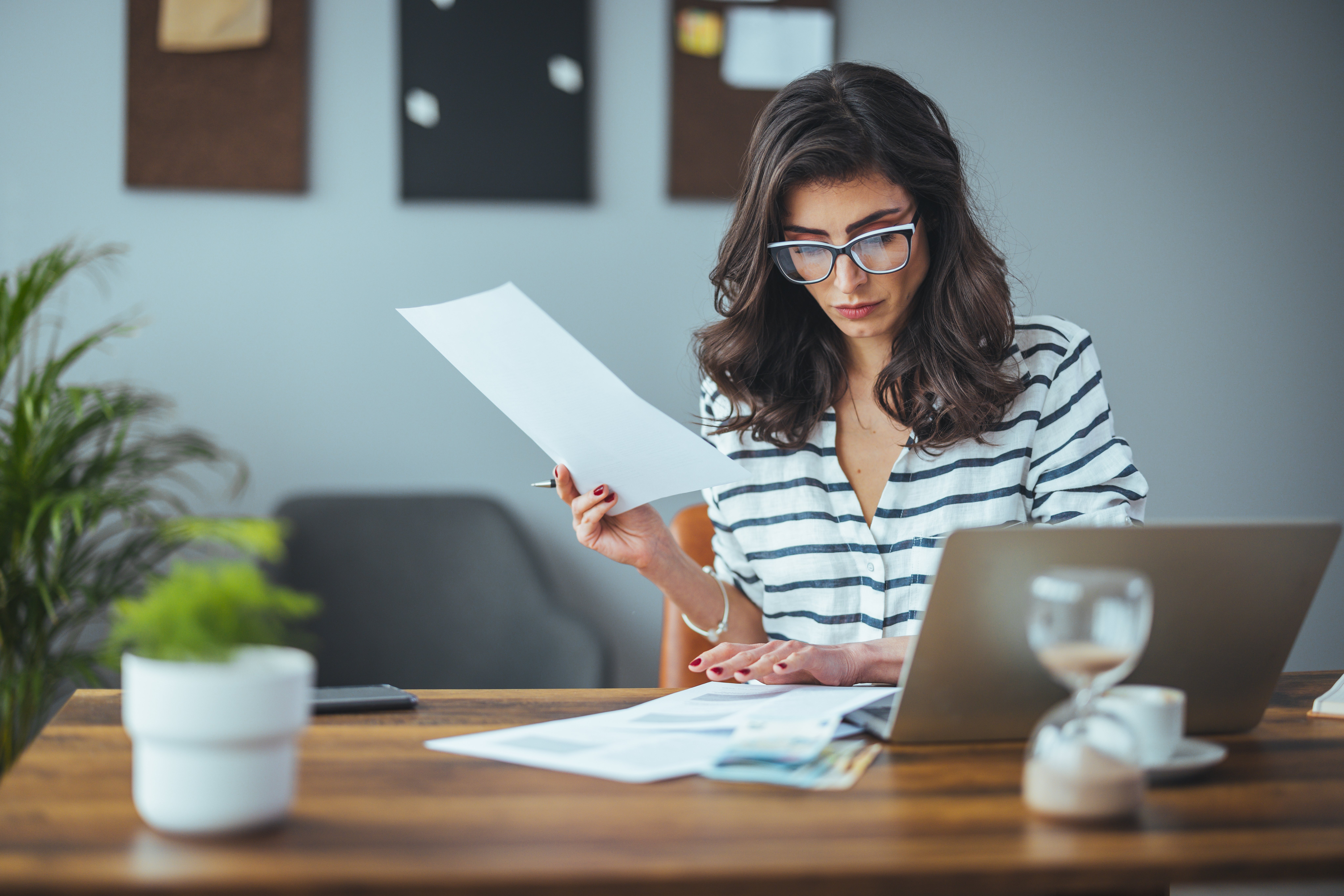 A smart business woman who keeps a paper account using a calculator, an old woman manages the account's finances, calculates the tax on the cash budget, plans to pay off a bank loan debt Adobe stock photo