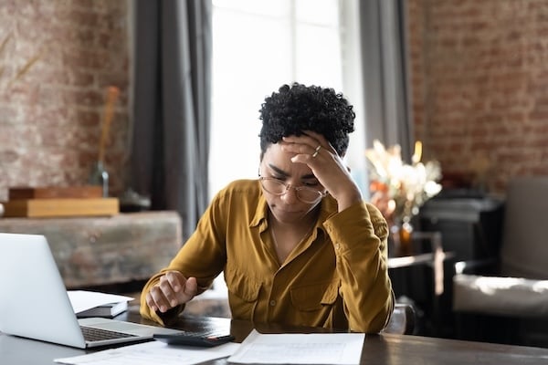 Unhappy frustrated young African American woman feeling stressed managing financial affairs Adobe stock photo