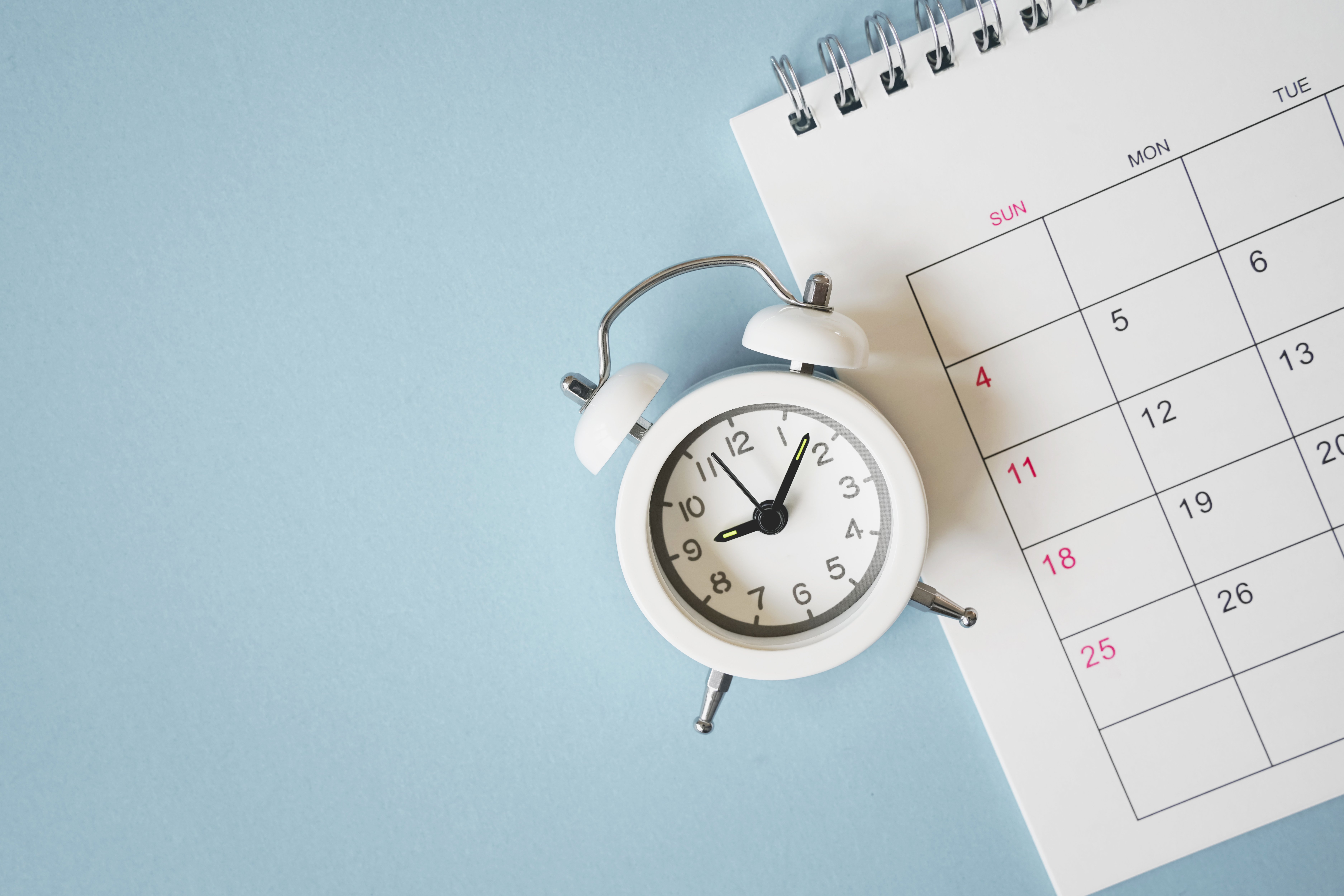 white analog alarm clock on calendar with grunge blue background
