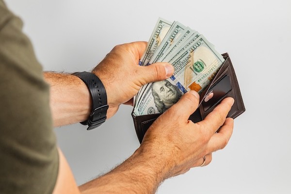 Person holds cash and wallet in hand with financial focus