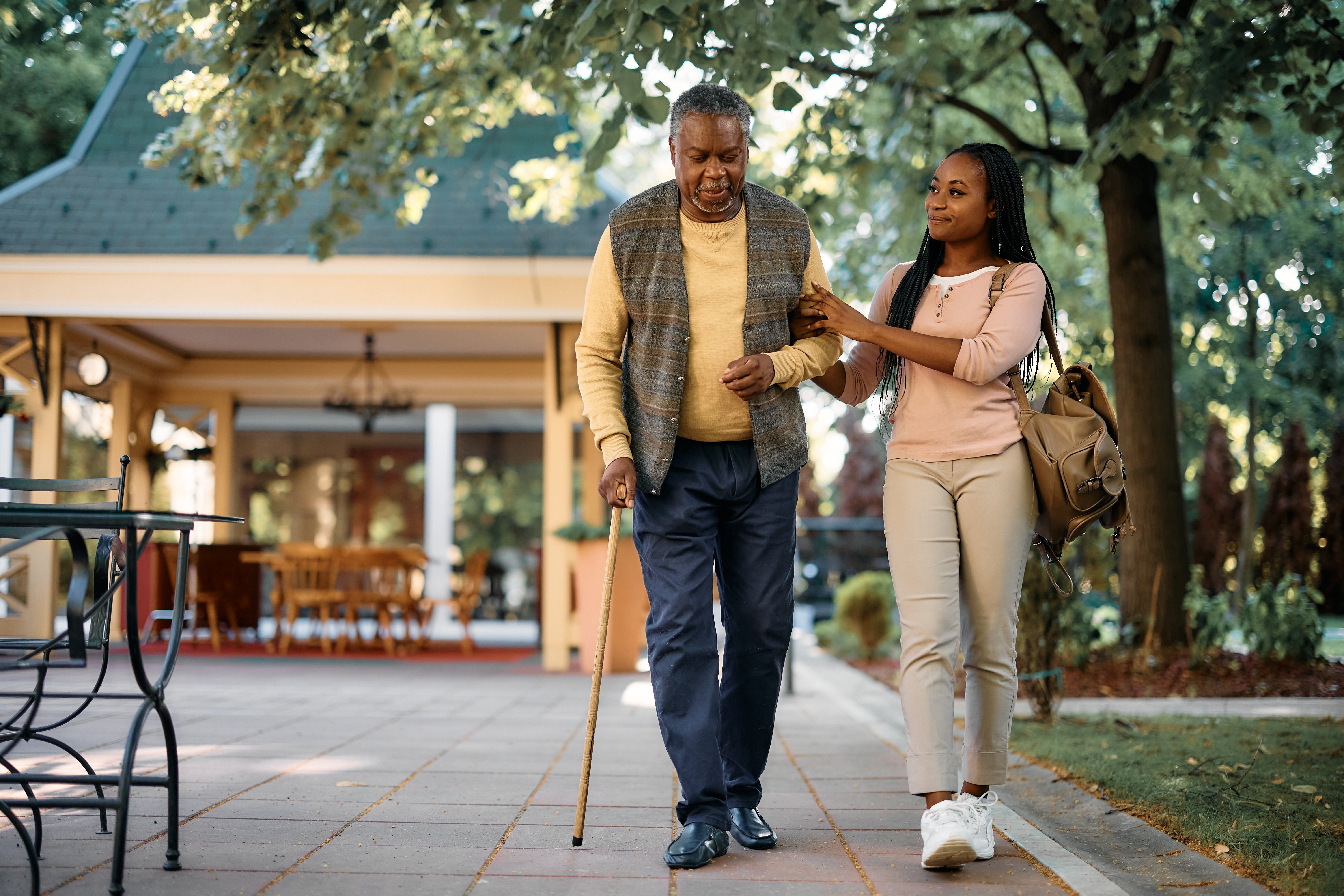 Happy African American woman walks with her senior father while visiting him at nursing home adobe stock image