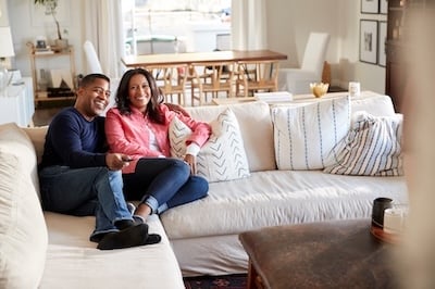 Middle aged couple reclining on the sofa in their living room watching TV Adobe stock photo