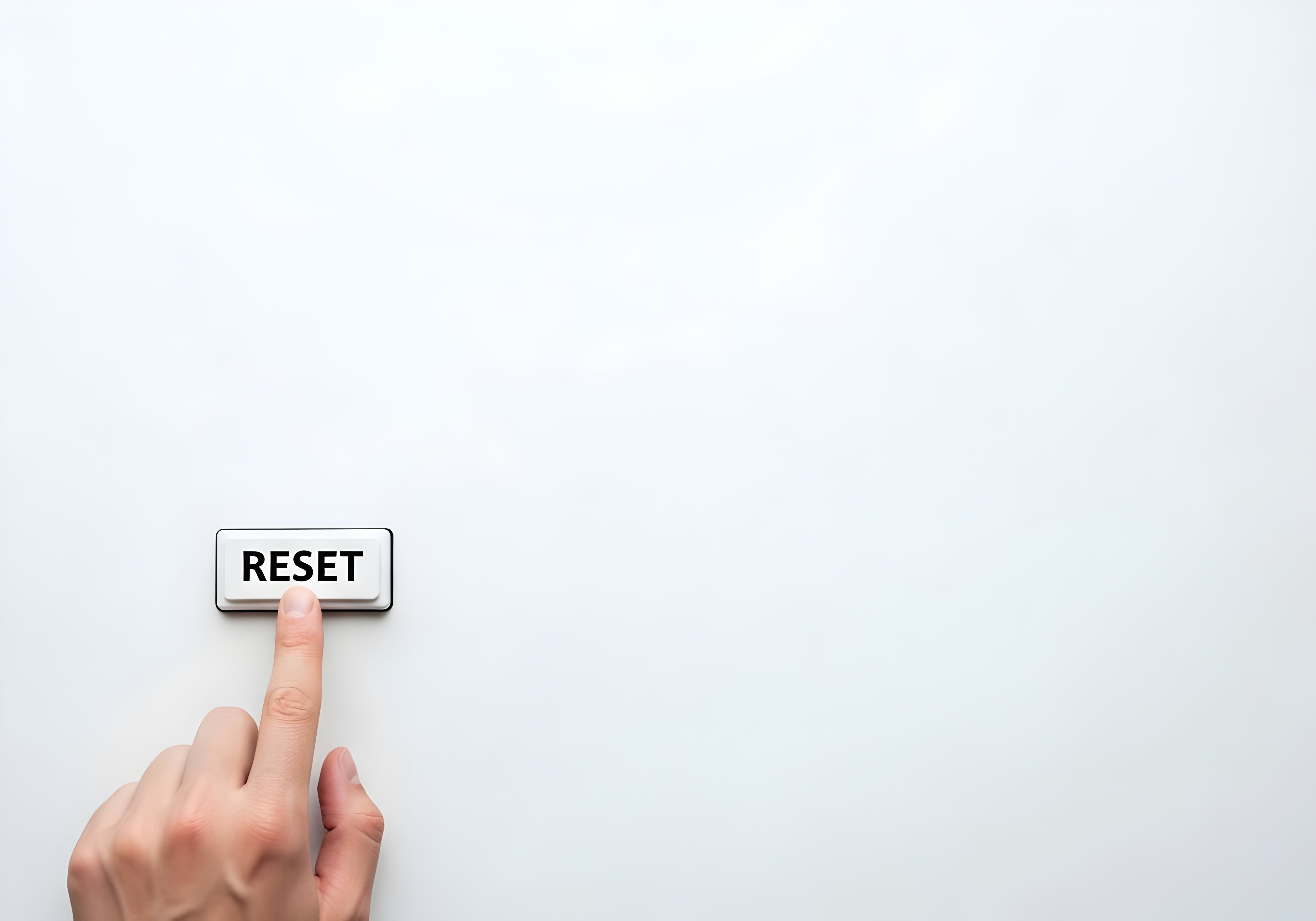 Finger pressing physical Reset button on white background with large copy space for fresh start concept