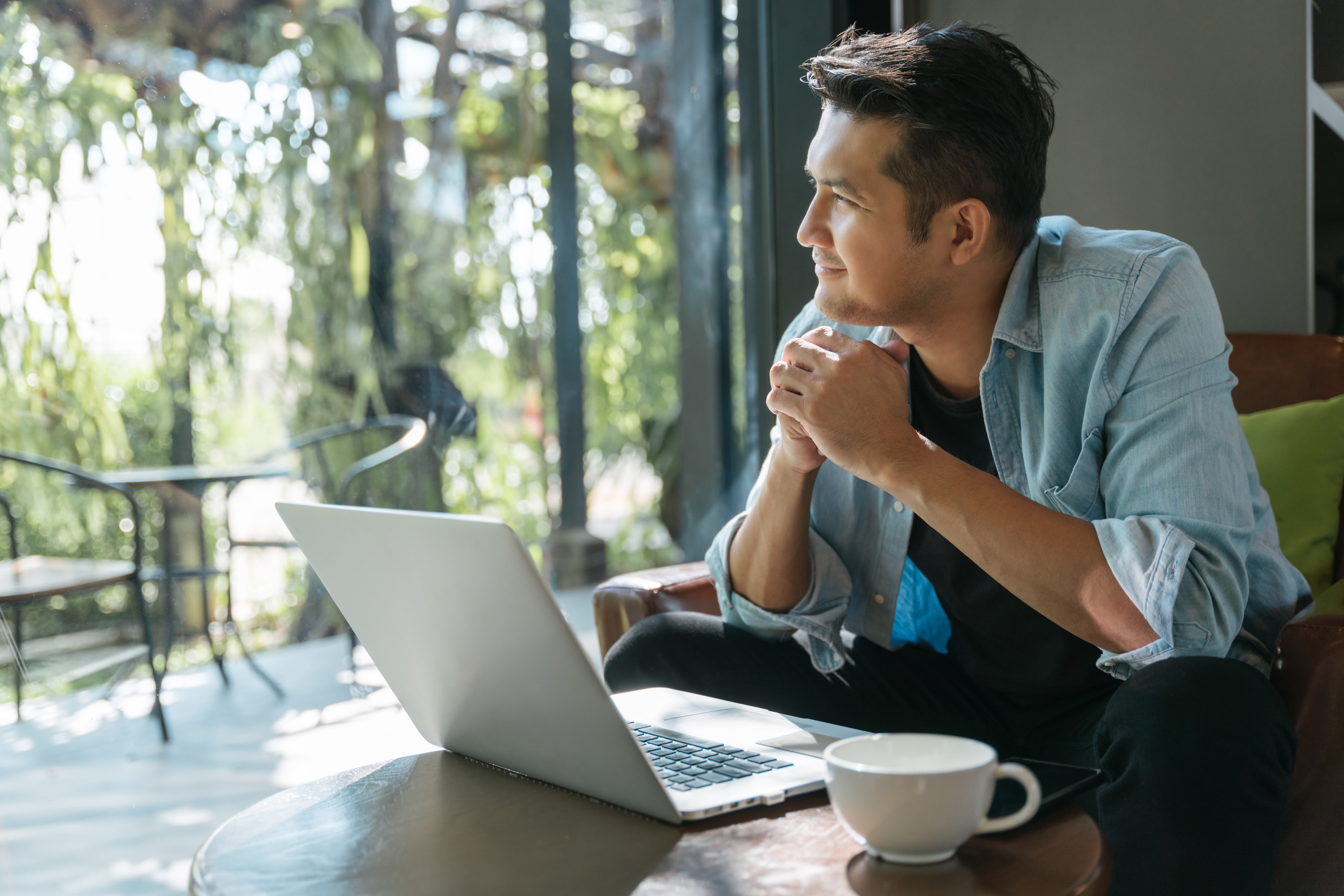 Asian handsome man sitting happily looking out of the window in a cafe