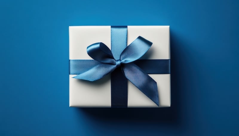 Beautifully wrapped gift box with blue ribbon on a blue background
