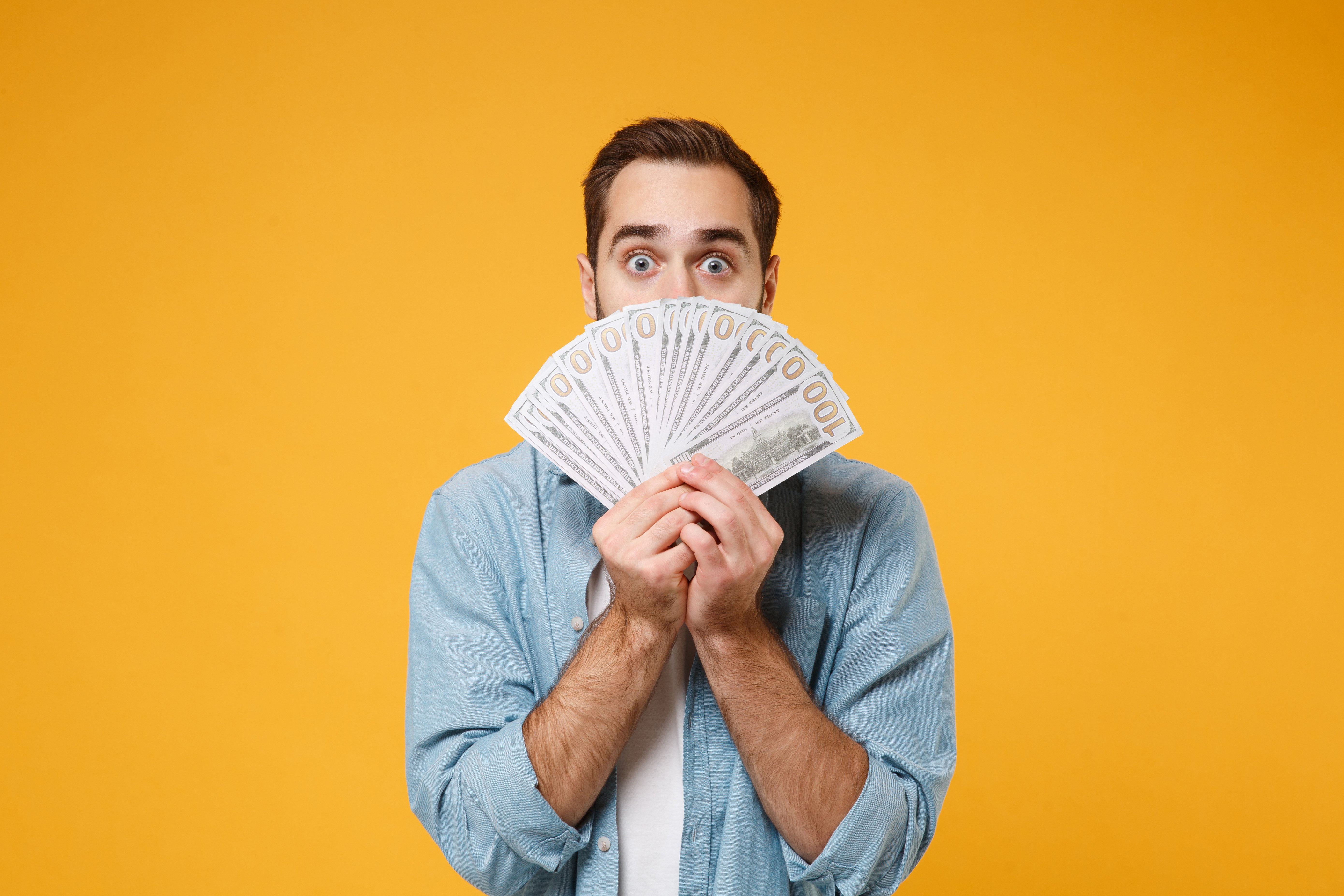  Downloaded    File #:  310005329 Shocked young man in casual blue shirt posing isolated on yellow orange background in studio. People lifestyle conce